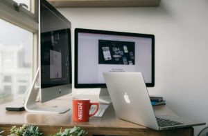A bright modern office setup with computers and a mug on a desk.