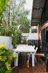 Exterior of contemporary building with white table and chairs surrounded with green plants in daytime